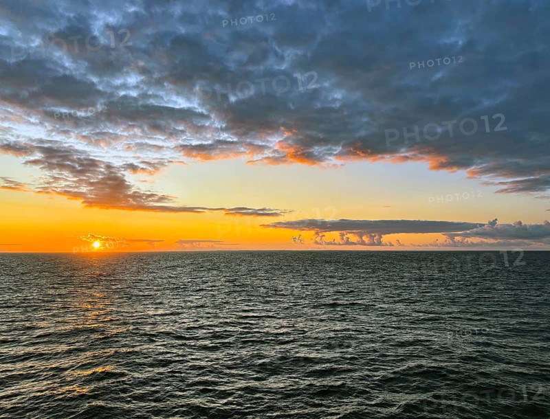 Tranquil ocean horizon at sunset with dramatic clouds and warm hues, Orkney Islands, Scotland, United Kingdom