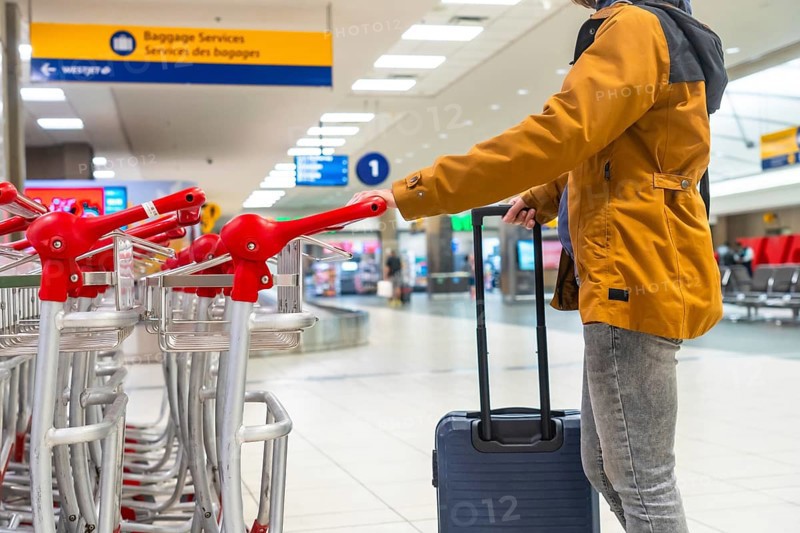 Tourist navigating the airport terminal with a luggage trolley, positioned near the baggage claim area, marking the start of an exciting journey after arrival