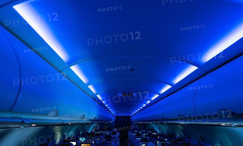 Blue cabin lights creating a relaxing atmosphere inside an airplane during a flight, with passengers sitting in their seats and enjoying the journey