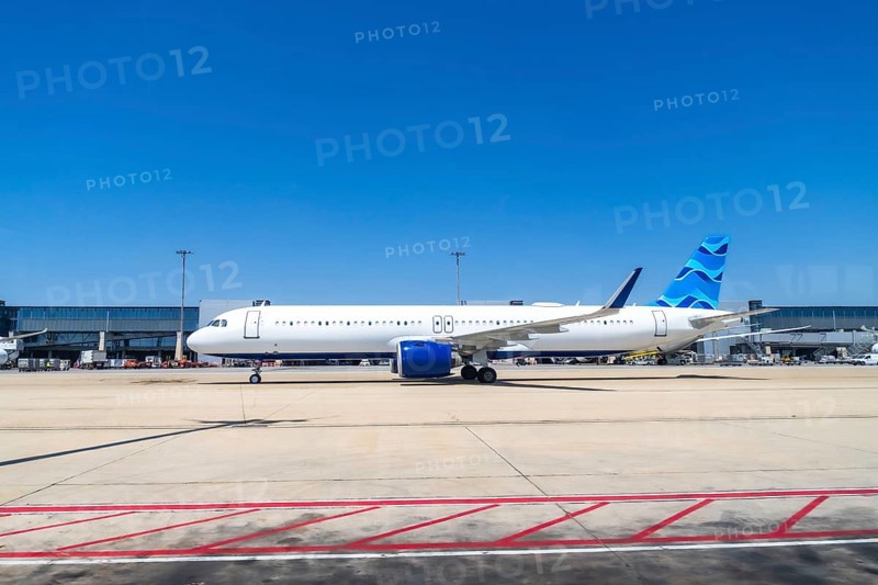 Modern passenger airplane parked on the tarmac at a bustling airport, preparing for its next flight under a clear, vibrant blue sky, highlighting the excitement of travel and aviation