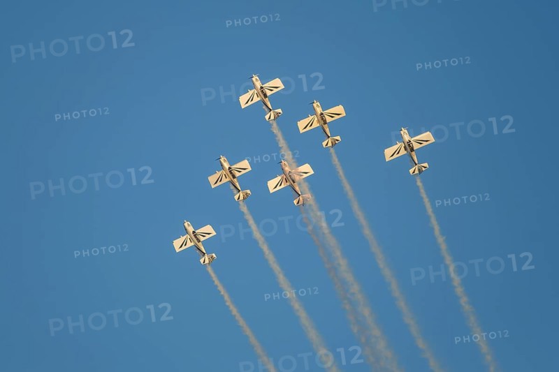 Stunt aerobatic planes performing stunts in blue sky with smoke trail. Concept of teamwork, collaboration, coordination, trust, precision, difficulty, challenge, speed, synergy