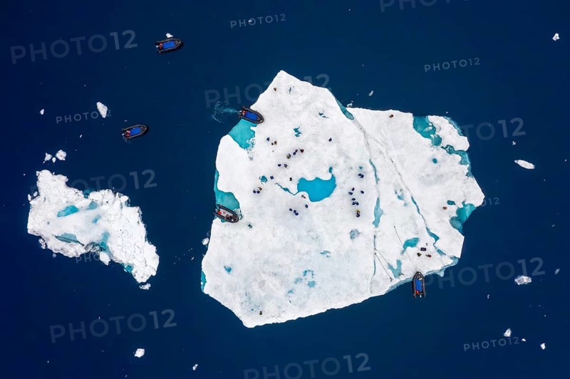 Aerial view over ecotourists from Iceland Pro Cruises walking on ice floe drifting in the Arctic Ocean in summer at Svalbard / Spitsbergen, Norway