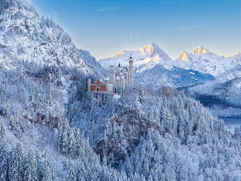 Neuschwanstein Castle surrounded by mountains in snow, in the warm light of sunrise, Schwangau near Füssen, Ostallgäu, Allgäu, Bavaria, Germany