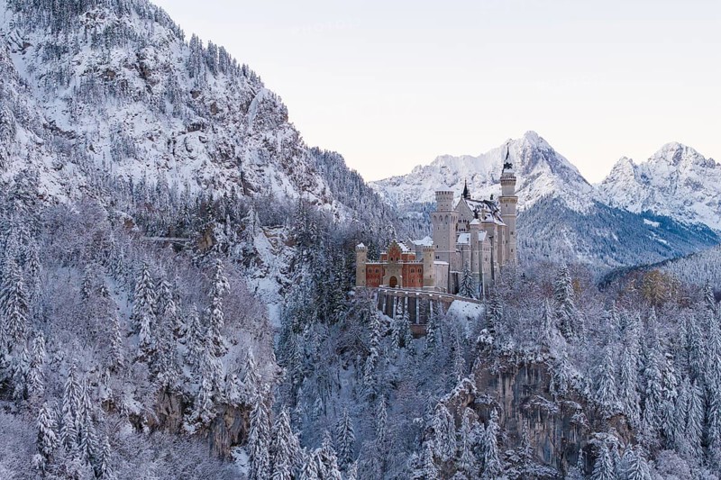 Neuschwanstein Castle in a snowy mountain landscape surrounded by trees, magical and quiet, Schwangau near Füssen, Ostallgäu, Allgäu, Bavaria, Germany