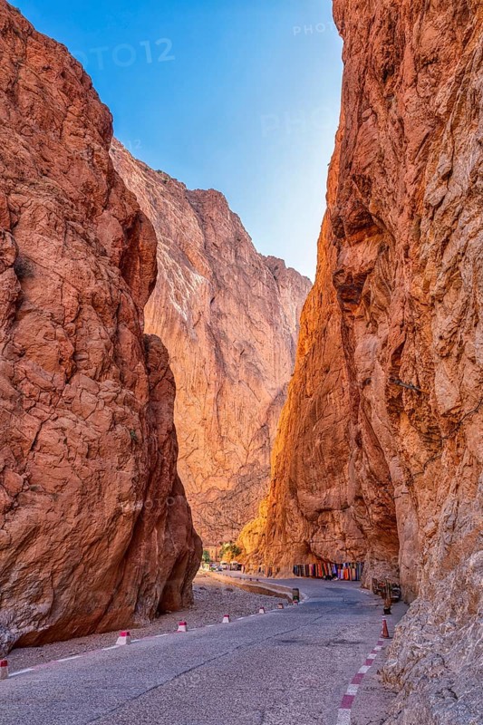Narrow road leads through dramatic red rock formations at dusk, Todra Gorge in Morocco