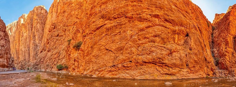 Panoramic view of gigantic red rock face under clear sky, Todra Gorge in Morocco