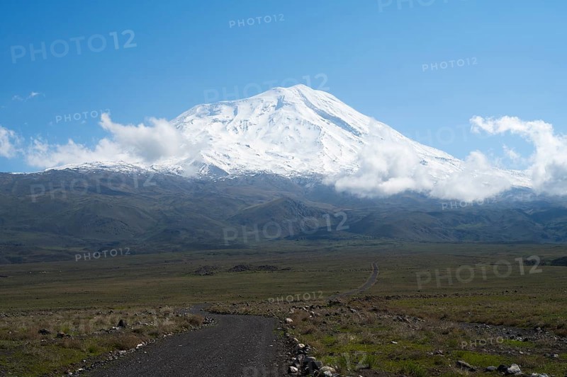 A snow-covered mountain rises majestically under a clear blue sky with scattered clouds, near Cevirme, Great Ararat, Büyük Agri Dagi, Dogubayazit, Dogubayazit, Dogubeyazit, Agri Province, East Anatolia, Turkey