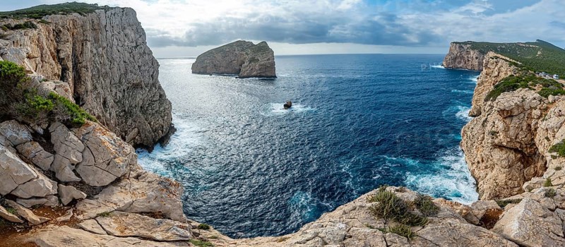 Steep cliffs by the sea and the rocky island of Isola Foradada, Belvedere Foradada, cliffs on the Capo Caccia headland, Alghero, Sardinia, Italy