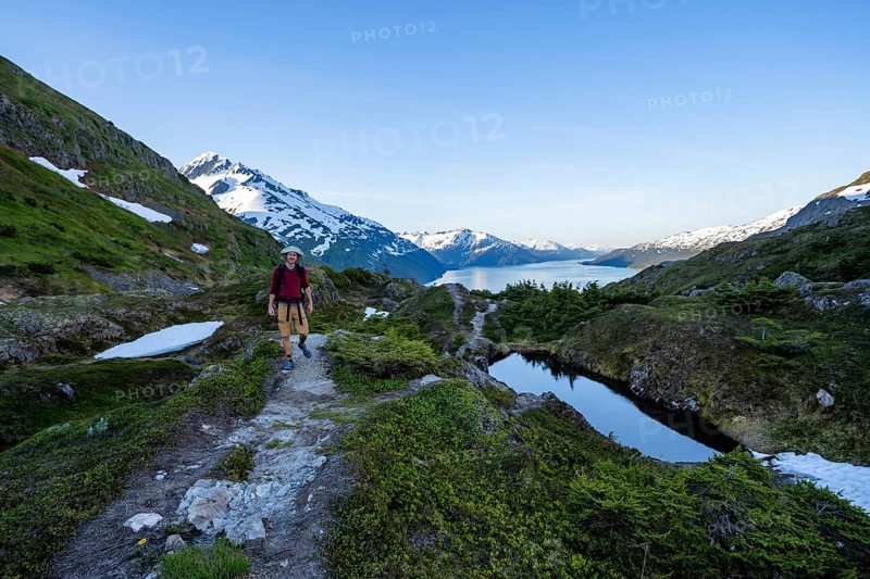 Hikers on Portage Pass, snow-covered mountains and Fjord Passage Canal, near Whittier, Alaska, USA