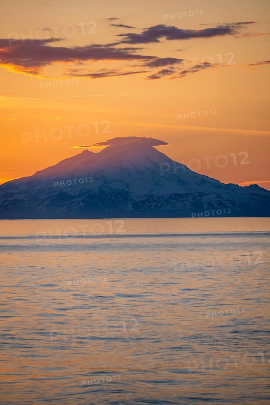 View of Cook Inlet on white mountain peaks of Mount Redoubt at sunset, picturesque golden light of the midnight sun, mountains of the Aleutian Range, Anchor Point, Anchor River State Recreation Area, Alaska, USA