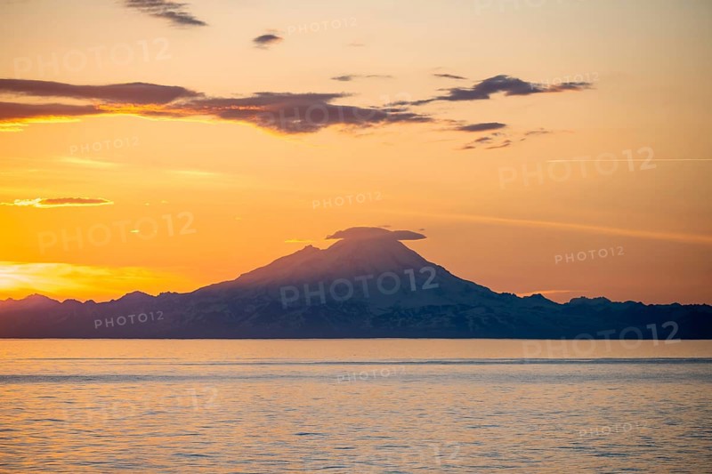 View of Cook Inlet on white mountain peaks of Mount Redoubt at sunset, picturesque golden light of the midnight sun, mountains of the Aleutian Range, Anchor Point, Anchor River State Recreation Area, Alaska, USA