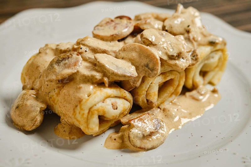 A tempting plate of stuffed crepes filled with savory meat and topped with a rich, creamy mushroom sauce. Perfect for a hearty lunch or dinner, this dish is comforting and flavorful