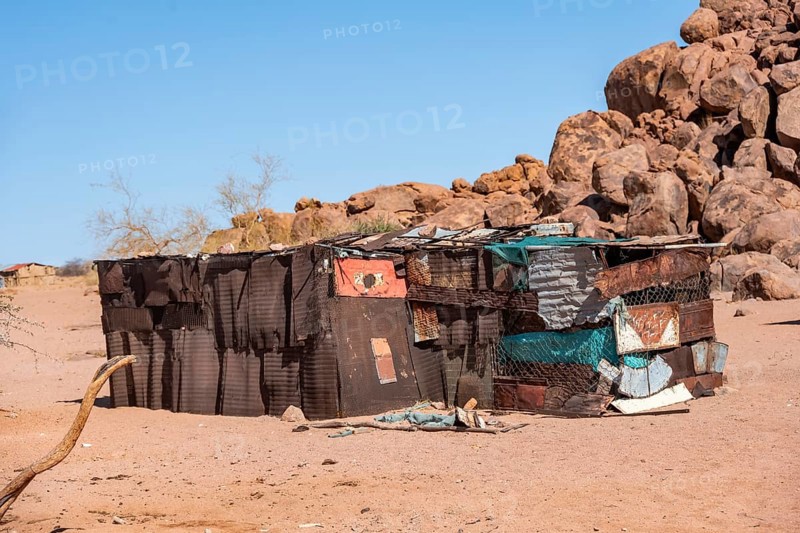 Simple poor huts made of corrugated iron and wood, desert landscape, barren landscape with hills of stacked rocks, Brandberg, Erongo, Damaraland, Namibia
