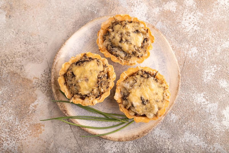 Tartlets with meat and cheese on brown concrete background. top view, flat lay, copy space