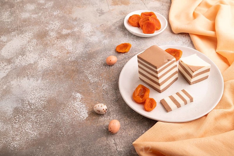 Cocoa and milk jelly with dried apricots on brown concrete background and orange textile, side view, copy space, minimalism