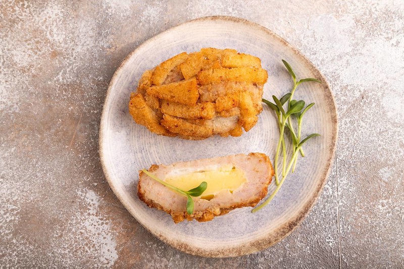 Chicken schnitzel on blue plate with microgreen on brown concrete. Diet, healthy eating. top view, copy space