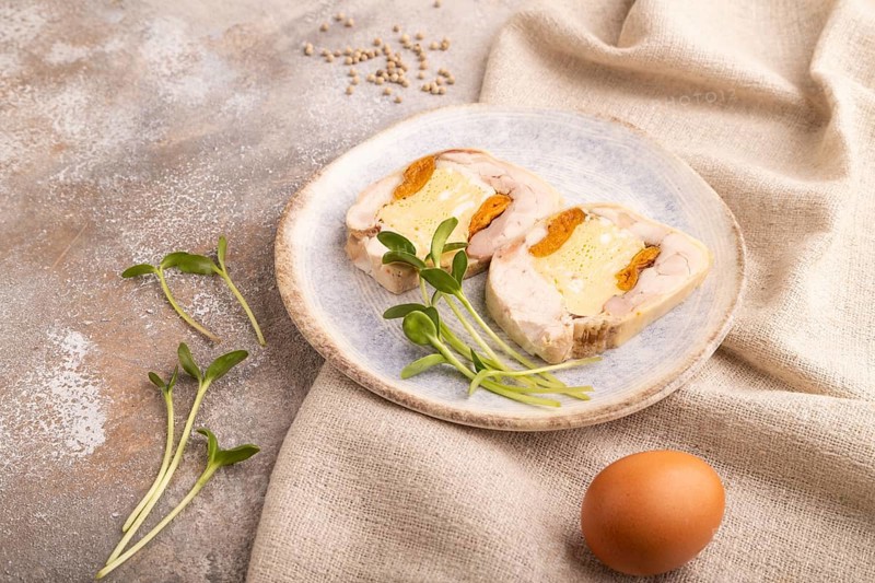 Chicken, egg and dried apricot meatloaf, microgreen on brown concrete background and linen textile. side view, close up