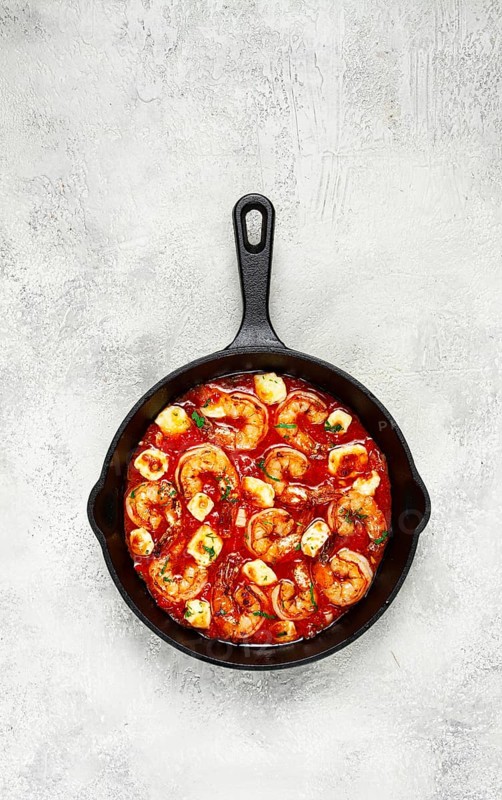 Greek saganaki, in an iron pan, saganaki with shrimp, shrimp in tomato sauce, with pepper and feta cheese, homemade, no people