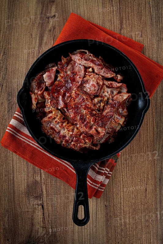 Crispy bacon, on a cast-iron skillet, on a wooden table, rustic style, no people