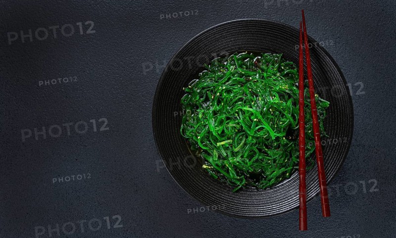 Chuka salad, made from fresh seaweed, with sesame dressing, served in a black bowl, with chopsticks