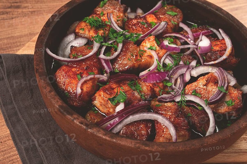 Fried meat, pork kebab, ketsi in a clay pan, with red onions and herbs, homemade, no people