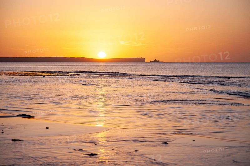 Sunrise over Jervis Bay — View of Point Perpendicular lighthouse. A ship on the horizon