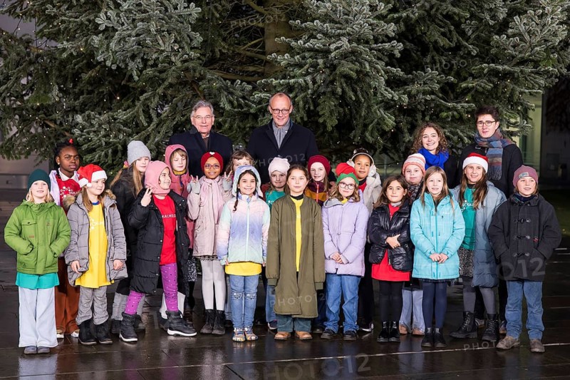 Friedrich Merz (CDU, Federal Chancellor of the Federal Republic of Germany) behind the Vocal Hero Children's Choir from Schöneberg elementary schools handing over the Christmas tree to the Federal Chancellery, Berlin, 28.11.2025