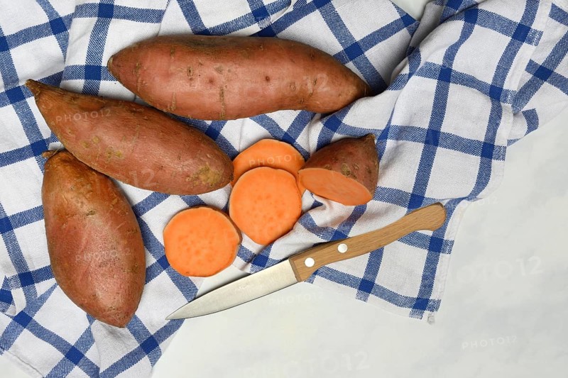 Sweet potatoes with kitchen knife on kitchen towel, Ipomoea batatas