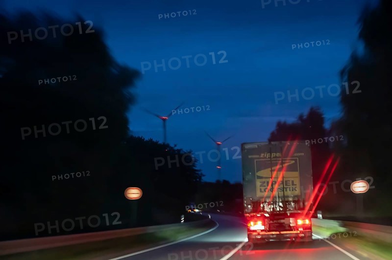 Truck on federal highway at night, wind turbine lights on the left, Schleswig-Holstein, Germany