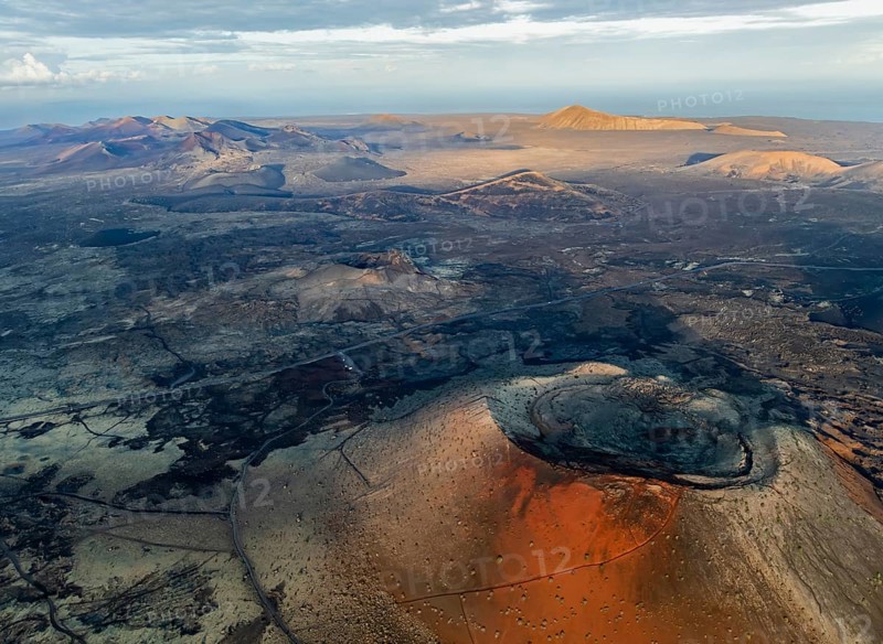 Caldera Colorada volcano, picturesque volcanic landscape with volcanic craters and lava fields in morning light, Parque Natural de Los Volcanes, aerial view, Lanzarote, Canary Islands, Spain