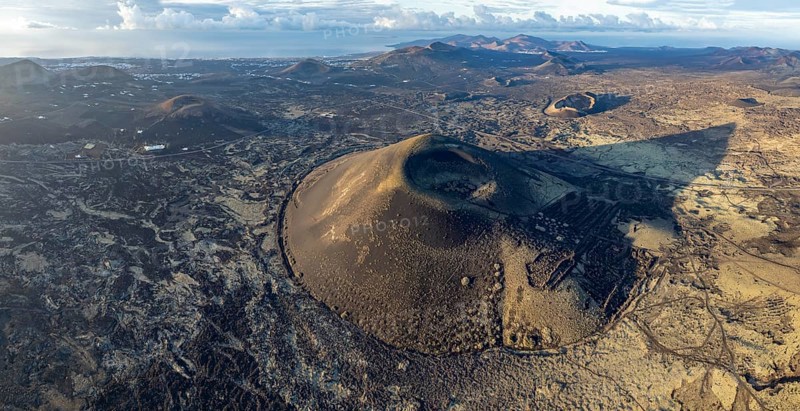 Montaña Negra volcano, picturesque volcanic landscape with volcanic craters and lava fields in morning light, Parque Natural de Los Volcanes, aerial view, Lanzarote, Canary Islands, Spain