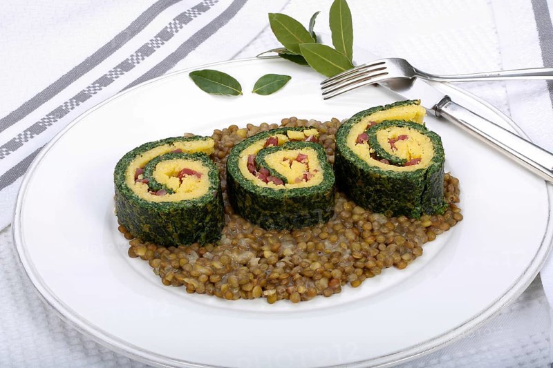 Southern German cuisine, polenta spinach roulade with alblentils served on serving platter, bay leaves, lentil vegetables, smoked meat, bacon cubes, healthy, food photography, studio, Germany