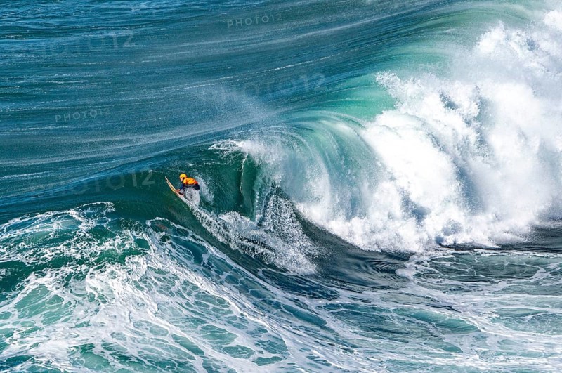 Surfers with their jet ski pilots in the Atlantic waves below Farol de Nazaré, Forte São Miguel, known as a surfer hot spot with monster waves between November and February of each year, Nazaré, Portugal