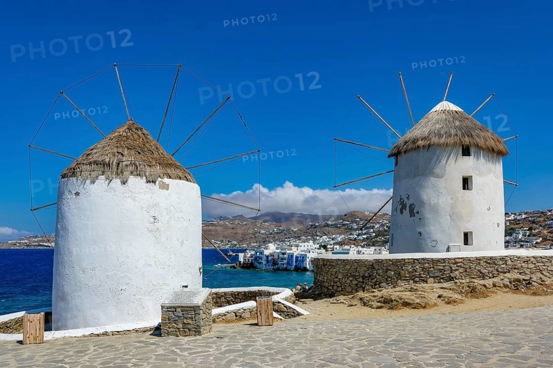 Mykonos, Cyclades, Greece - The six sixteenth-century windmills, lined up on a hill above Mykonos Town, Mykonos Chora, are the island's landmark. At the back, right by the sea, are the colorful houses of Little Venice. Mykonos is part of the Cyclades archipelago in the Aegean Sea