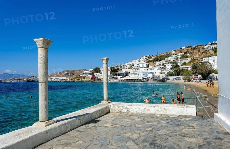 Mykonos, Cyclades, Greece - Tourists and locals like to bathe at the small town beach Paralia Cheras Mikonou right at the old port in the old town of Mykonos Town, Mykonos Chora. Mykonos is part of the Cyclades archipelago
