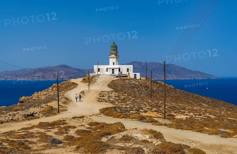 Mykonos, Cyclades, Greece - The Armenistis lighthouse in the north of the island is a landmark and a popular destination for tourists. In the back is the island of Tinos
