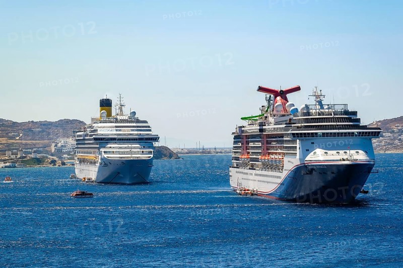 Mykonos, Cyclades, Greece - cruise ships CARNIVAL MIRACLE and COSTA FORTUNA are located in the bay off Mykonos City. Old town with windmills. Cruise ships bring tourists to shore