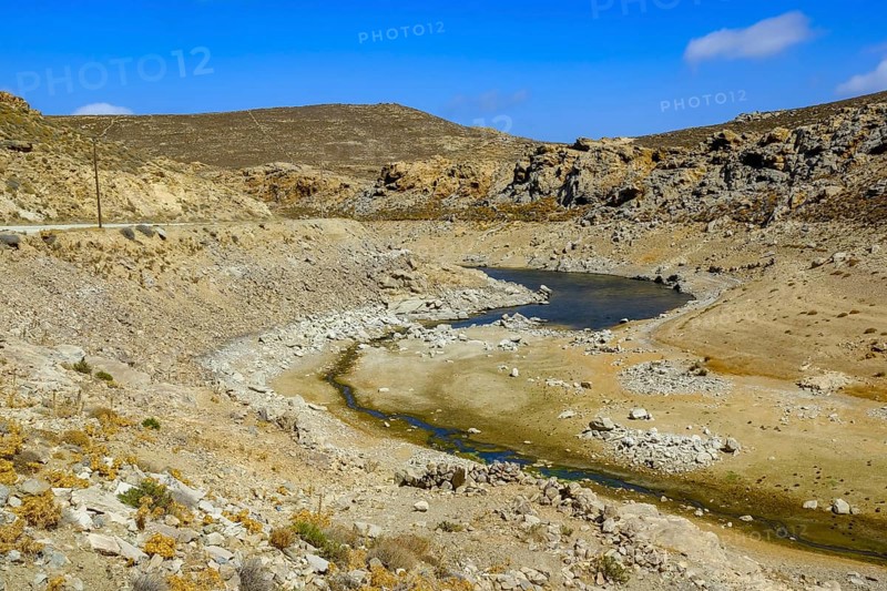 Mykonos, Cyclades, Greece - Dry Fokos Reservoir near Ano Mera. The Mykonos Municipal Water Supply and Sewage Management Company has two dams, Marathi Reservoir and Fokos Reservoir, to supply water to the island. Due to the prolonged drought, both are almost empty and are not being used