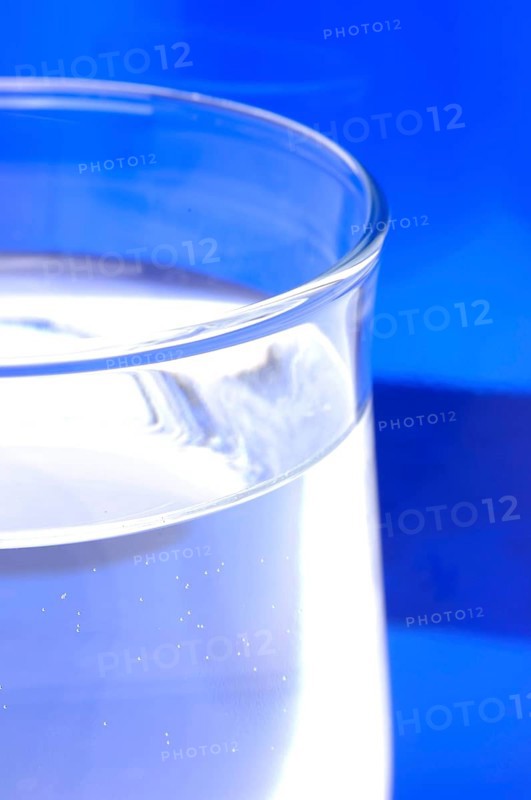 Glass with mineral water, small carbonated pearls on the edge of the glass, drinking water
