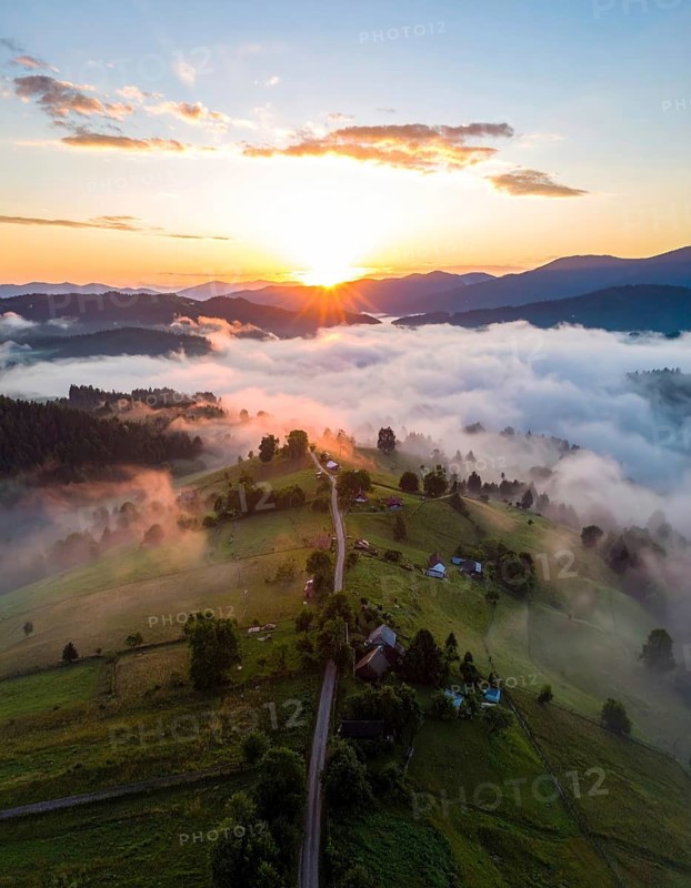 Sunrise over a fog covered village in a rural landscape, golden morning light, serene autumn atmosphere, hills and mountains in the background, AI generated