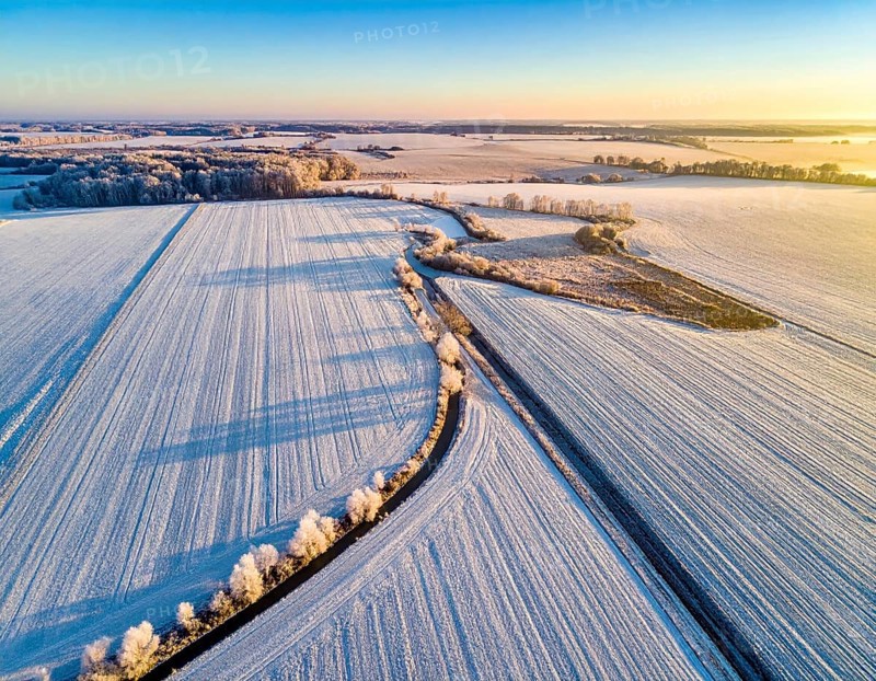 Bird Eye Perspective of Frost Covered Farmland. Seasonal Agricultural Scenery, winter and autumn scene, blue sky with golden light at sunrise, AI generated