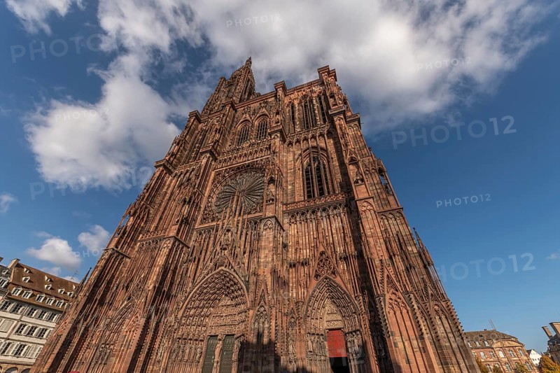 Strasbourg's Notre Dame Cathedral stands majestically there. Its magnificent architectural details are clearly visible under the blue, cloudy sky. Bas Rhin, Alsace, France