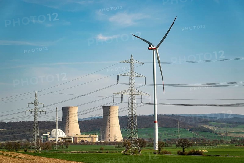 Distant view of the Grohnde nuclear power plant, with wind turbine, electricity pylons and power lines in the foreground, Emmerthal, Lower Saxony, Germany