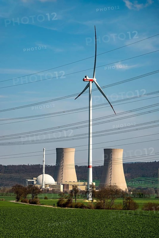 Distant view of the Grohnde nuclear power plant, dominated by a wind turbine, power lines in the foreground, Emmerthal, Lower Saxony, Germany
