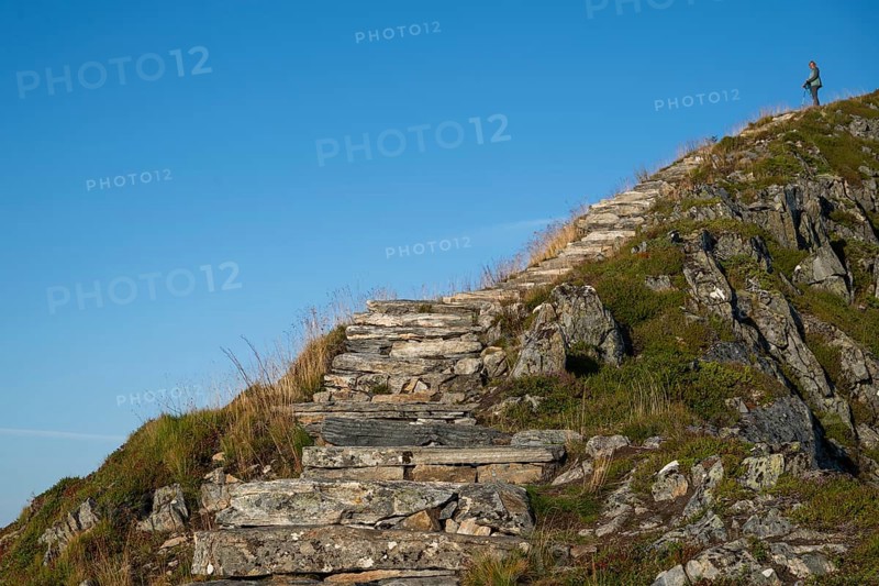 Woman with hiking poles walking up Rørsethornet stone stairs, with 3292 steps one of the longest continuous stone stairs in the world, Sherpat stairs or Midsund stairs or Midsundtrappene, Rørsethornet hike, Otroya or Otrøya island, Møre og Romsdal, Norway