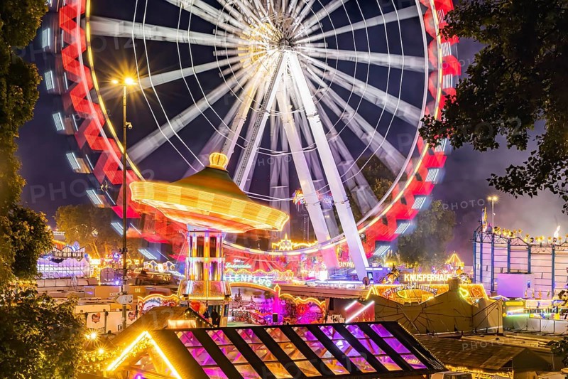 Folk festival in Stuttgart. The 178th Cannstatter Volksfest on the Wasen is one of the most important traditional festivals in Germany. Ferris wheel, chain carousel and other amusement park attractions, light effects at night. Stuttgart, Baden-Württemberg, Germany