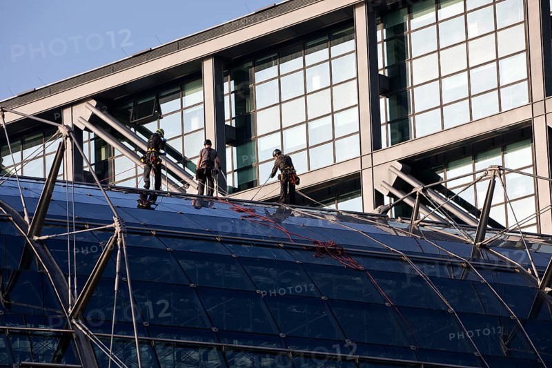 Three male glass cleaners abseiling down a glass roof of Berlin Central Station to clean windows, Berlin, Germany