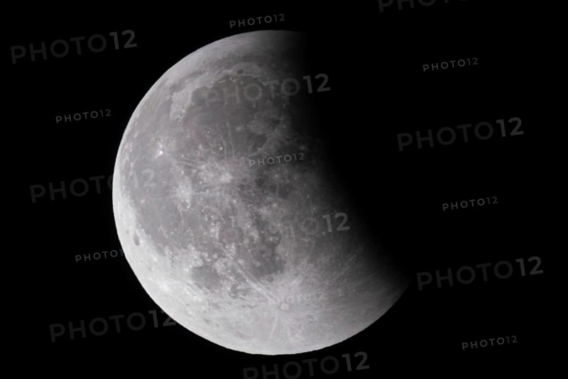 After a total lunar eclipse, the moon appears shortly after its rise in the evening sky as a so-called blood moon in front of it then begins to emerge from the Earth's umbra, Frankfurt am Main, Hesse, Germany