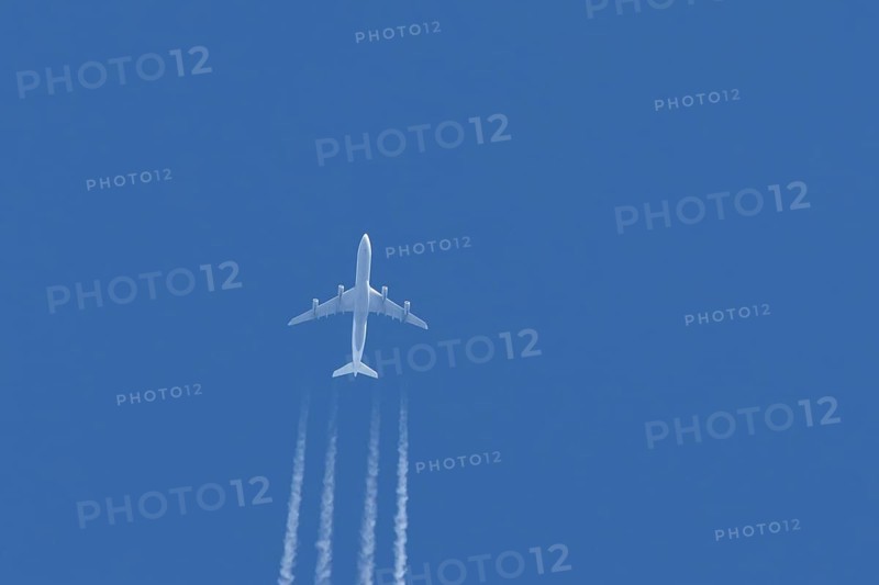 Airbus A340-300 jet aircraft of Lufthansa airlines in flight in a blue sky with vapour trails or contrails behind, England, United Kingdom