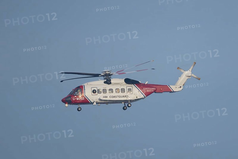 Sikorsky S-92A helicopter of the UK HM Coastguard flying in a blue sky, England, United Kingdom